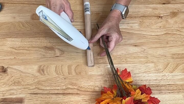 Applying hot glue to the plunger for the fall tree craft