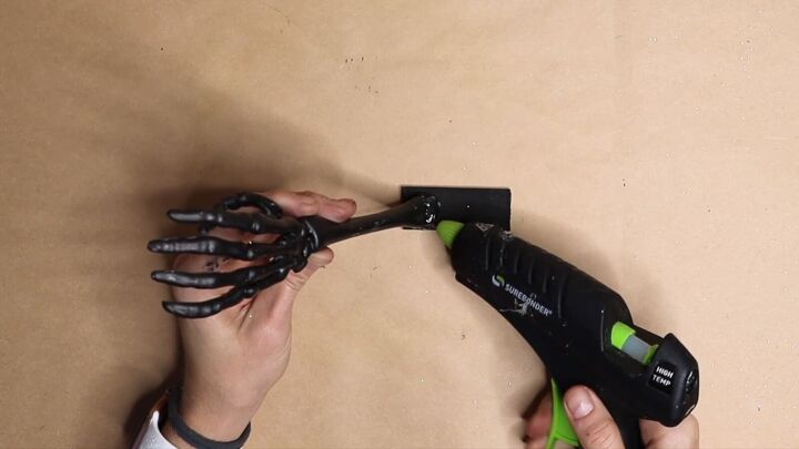 Hot glue the skeleton hand to the wood