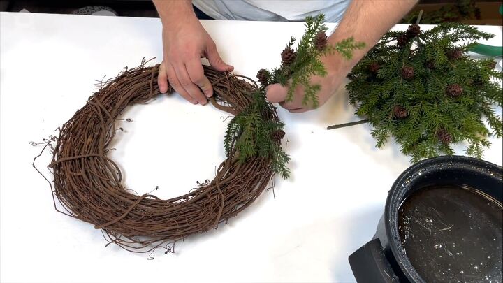 Gluing the pine stems to the grapevine wreath