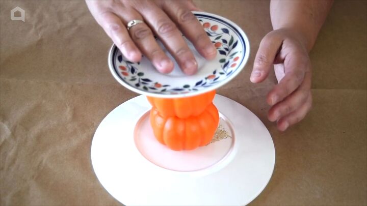 Connecting two thrift store plates with foam pumpkins to create a DIY cake stand