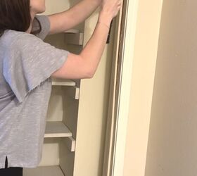 diy murphy puerta librera, Una mujer utiliza un martillo y una palanca para quitar la moldura de la puerta