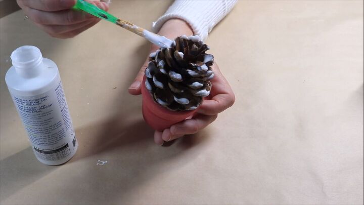 Applying craft glue to the tips of the pine cone