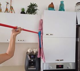 Using a squeegee wrapped with a cloth to clean kitchen cabinets
