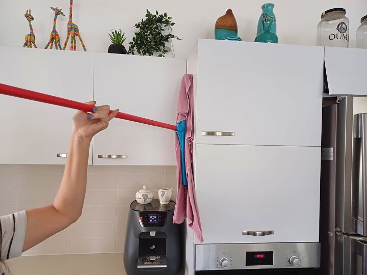 Using a squeegee wrapped with a cloth to clean kitchen cabinets