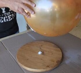 Attaching a rubber ball to a round plywood base with construction adhesive