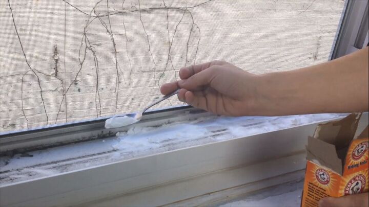 pour vinegar into your windowsill for an easy cleaning hack, Spooning baking soda onto the dirty window tracks