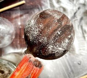 adornos vintage diy una sencilla gua de manualidades navideas, Una persona sostiene una bola de madera con un palo