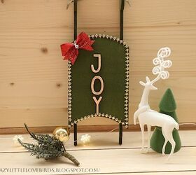 decoracin navidea con trineo de dollar tree, Trineo verde con lazo rojo y gemas doradas sobre una mesa de madera