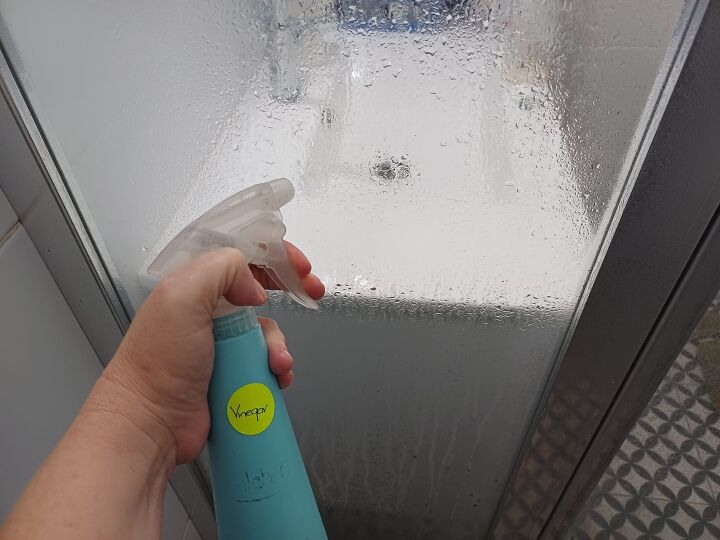 clean shower door, Spray vinegar onto the glass of the door