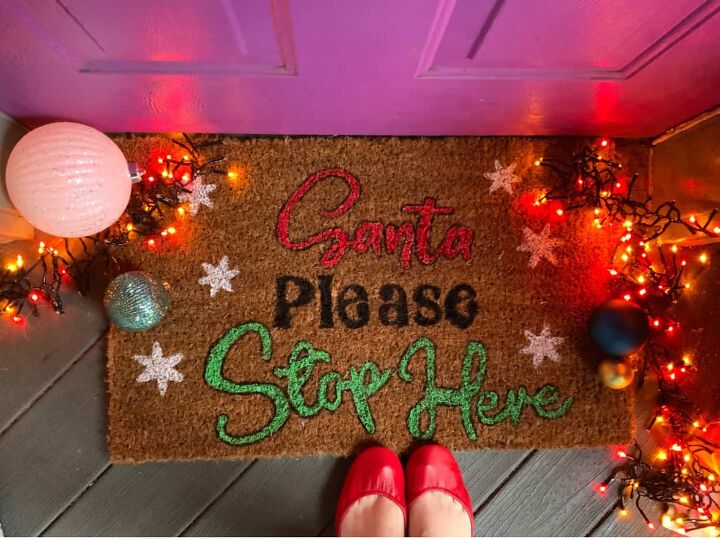 DIY doormat on a front porch with Christmas lights and ornaments