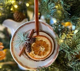 13 ideas de bricolaje para hacer adornos con naranjas secas, Adorno de rodajas de naranja en una rodaja de madera colgando delante de un plato de porcelana en el rbol de Navidad