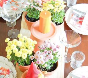 Velas amarillas y rojas en una mesa de oto o con crisantemos y macetas