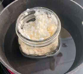 receta casera de mantequilla de madera, Un frasco de bolitas de cera de abejas en una olla en la estufa