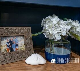cmo hacer divisiones de cajones personalizadas y sencillas, Un jarr n azul marino de Pottery Barn con hortensias blancas enmarcado con una foto de familia y un d lar de arena