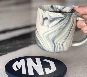 posavasos diy decoupage una tapa de tarro de vela upcycle, Una taza de caf colocada sobre un posavasos con monograma en la tapa de una vela