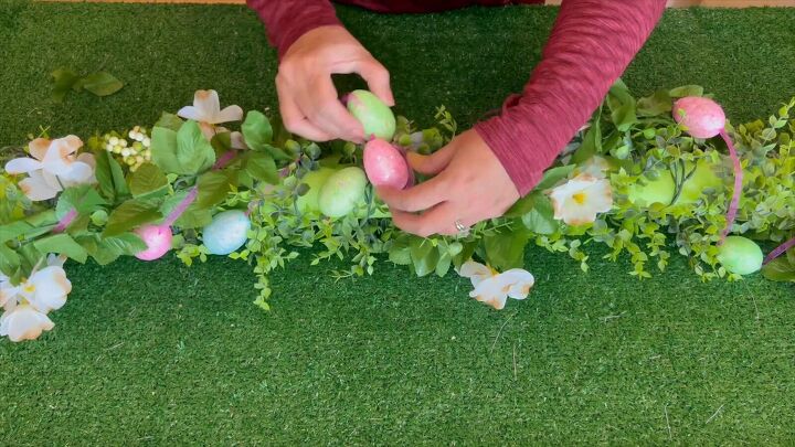 Adding a festive touch with a string of eggs wrapped around the garland base