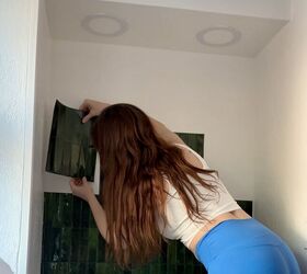 cmo hacer que la remodelacin de un medio bao lleve el look de sombro a glamuroso, Mujer aplica azulejo de pelar y pegar a la pared
