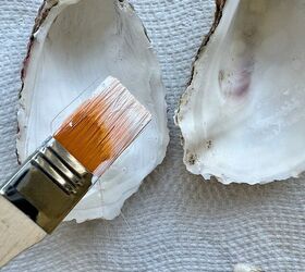 concha de ostra, Un pincel descansando sobre una superficie de textura blanca junto a dos conchas de ostra vac as