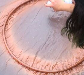 Spray-painting a hula hoop with metallic paint
