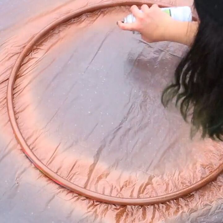 Spray-painting a hula hoop with metallic paint
