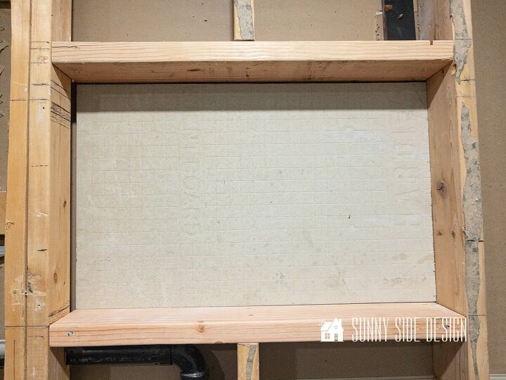 Cement backer board is secured to the back of the shower niche with construction adhesive