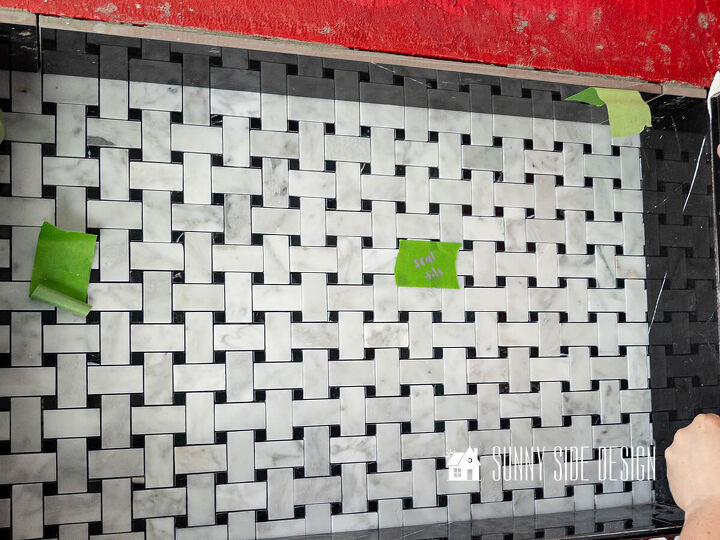 Black and white basketweave marble tile is placed on the back wall of the shower niche with black marble tile is placed on the 4 sides