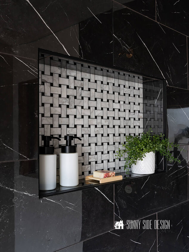 Tiled shower niche with Carrara marble basket weave tile and black marble shower wall tile Styled with pink marble soap black and white pump bottles and a plant
