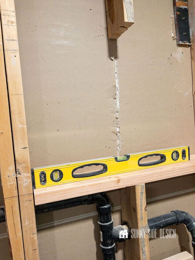 A level placed on the board for the shower niche checking for levelness