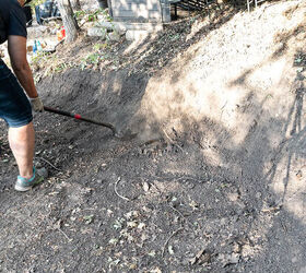 Woman digs with a shovel to create a gentle slope for a stone retaining wall