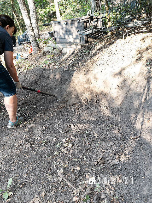 Woman digs with a shovel to create a gentle slope for a stone retaining wall
