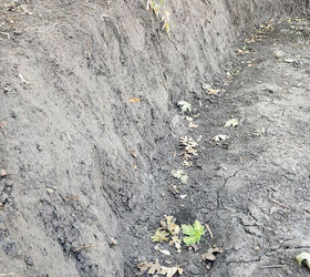 A trench is dug into the dirt for the first row of rocks for building a retaining wall
