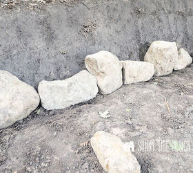 First row of rocks are placed in a trench for the retaining wall