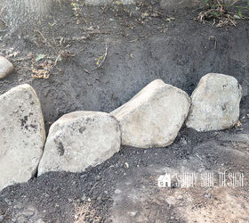 First row of rocks are placed in a trench for the retaining wall