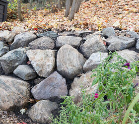 Completed rock retaining wall with autumn leaves and a green plant