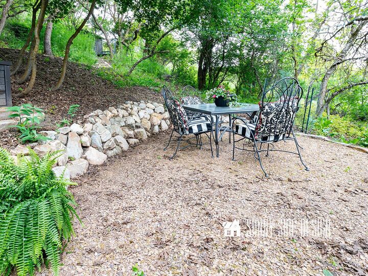 Gathering area with a dining table in a backyard with a slope and a small retaining wall