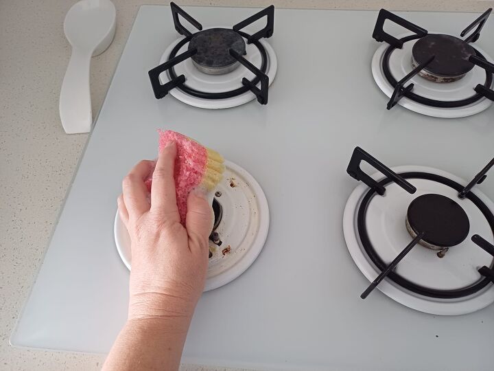 Sponge and frozen dishwashing cube scrubbing a greasy stovetop