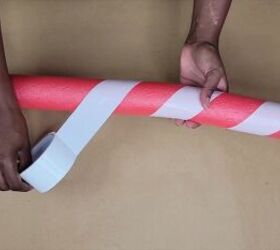 Wrapping the pool noodle Christmas decoration with white tape to create a candy cane look