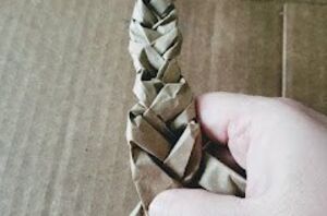 She starts braiding strips of brown packing paper for an Easter idea we've never seen