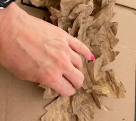 A woman adheres a paper maple leaf to the jute for the fall leaf garland