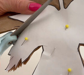 With a maple leaf template pinned to brown packing paper a woman cuts out the leaf shape