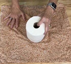 She places a roll of toilet paper on a piece of fabric for easy and delightful fall decor