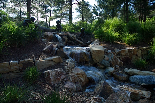 water features through walls, gardening, landscape, outdoor living, ponds water features, wall decor, Beautiful bronze statuary accent a pondless waterfall built in this wooded backyard at Castle Pines CO