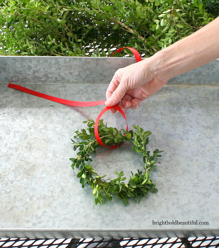 diy boxwood mini wreaths, crafts, seasonal holiday decor, 4 Take your red ribbon and tie one knot on the wreath and tie another knot around 6 apart 5 This second knot will allow you to hang your wreath on a hook or door knob