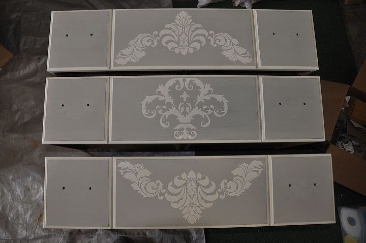 old maple dresser turned french country chic, painted furniture, I then trimmed it out in Old White It was tedious work cutting in around the raised panels but it will be worth it in the end Since I was using French linen I decided to give it a French country look by adding a few stencils