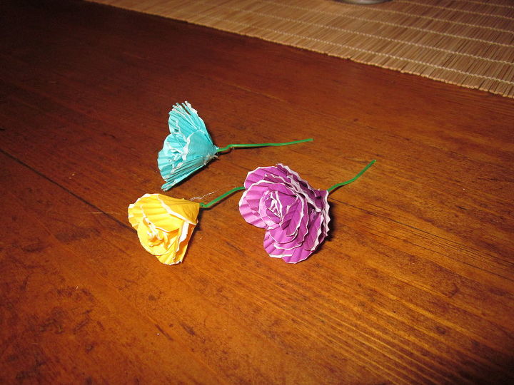 flores que fiz para um casamento de amigos, Forros de cupcake pequenos e multicoloridos enrolados em um pequeno clipe de papel verde presos com cola quente
