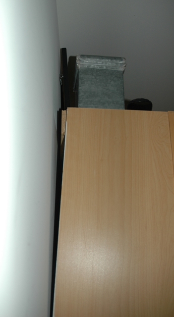 gabinete se inclina na parte superior em uma extremidade, Voc pode ver o peda o de madeira composta sendo dobrado e que n o h suporte fixo na parede pr ximo a essa extremidade
