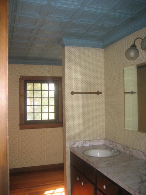 our florida bungalow bathroom redo, bathroom ideas, home decor, woodworking projects, The old bathroom old tin ceiling that had mold and rust and old double vanity that was falling apart and some dizzying wallpaper