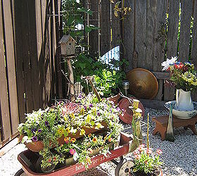repurposed red wagons made into planters in front of a bed spring trellis fill a back, gardening, repurposing upcycling, Old forgotten wagons with a new life as adorable planters I least I think they re lovely sit in front of a bedspring trellis The mirror behind the trellis is from a closet door