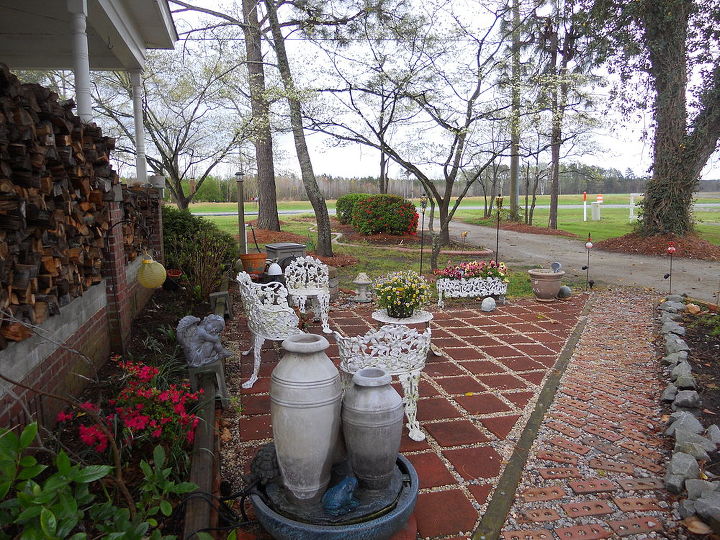 flower gardening turning a dead area into a southern style courtyard, decks, flowers, outdoor furniture, outdoor living, The courtyard is divided into two halves by a brick walkway Neighbors and friends gave us a lot of cuttings and flower bulbs One friend was moving and had no place to put her cast iron lawn furniture When she visited she said she had something for me and made me a gift of the furniture which is almost 100 years old Inexpensive mini pansies and trailing pansies offer color and southern charm to this furniture We are enjoying what was once a horrible eyesore