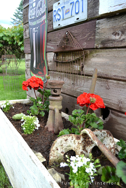 a rustic shed made from reclaimed lumber, doors, outdoor living, repurposing upcycling, Junky relics chime in well with bright red geraniums